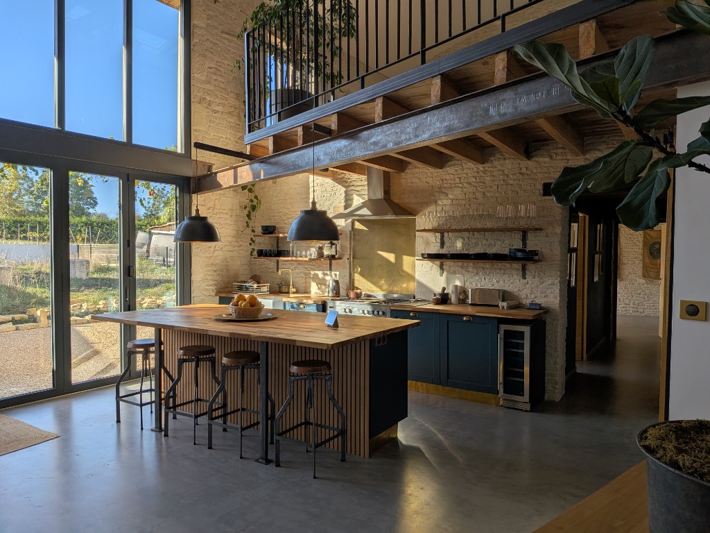 Renovated rustic French barn kitchen with warm lighting and wooden island