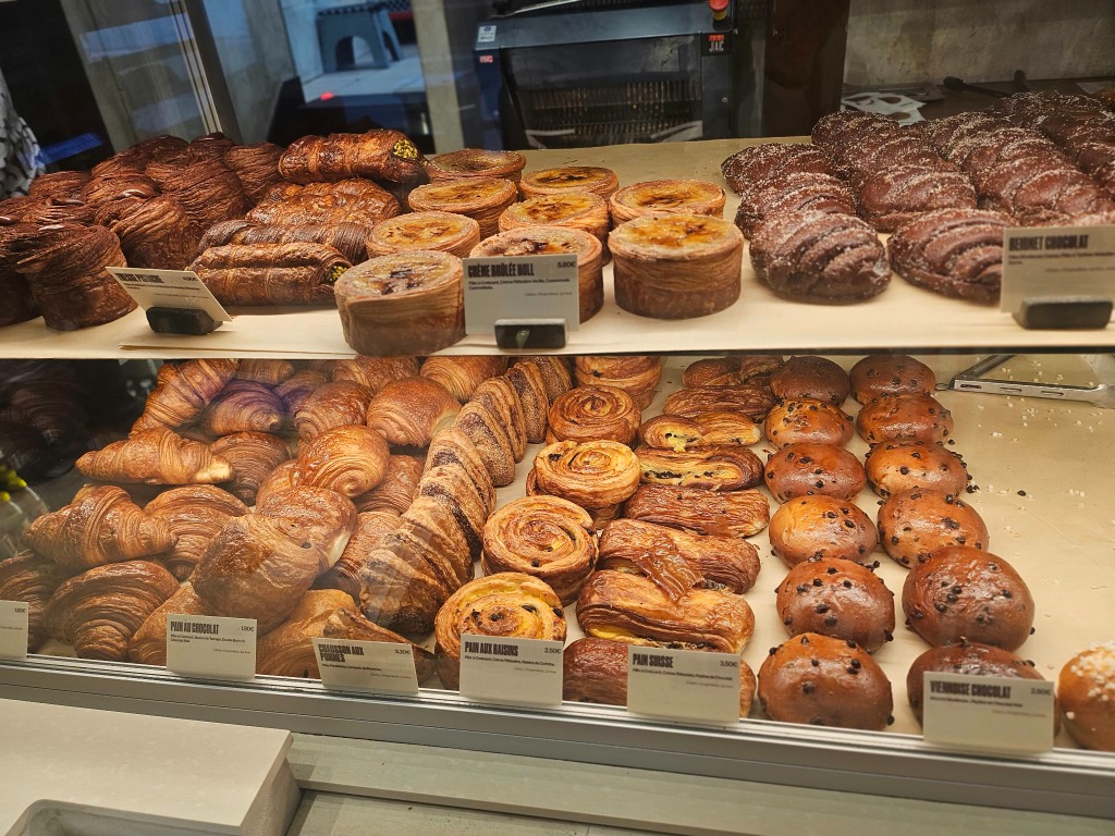 Fresh French bakery display case filled with golden croissants and pain suisse