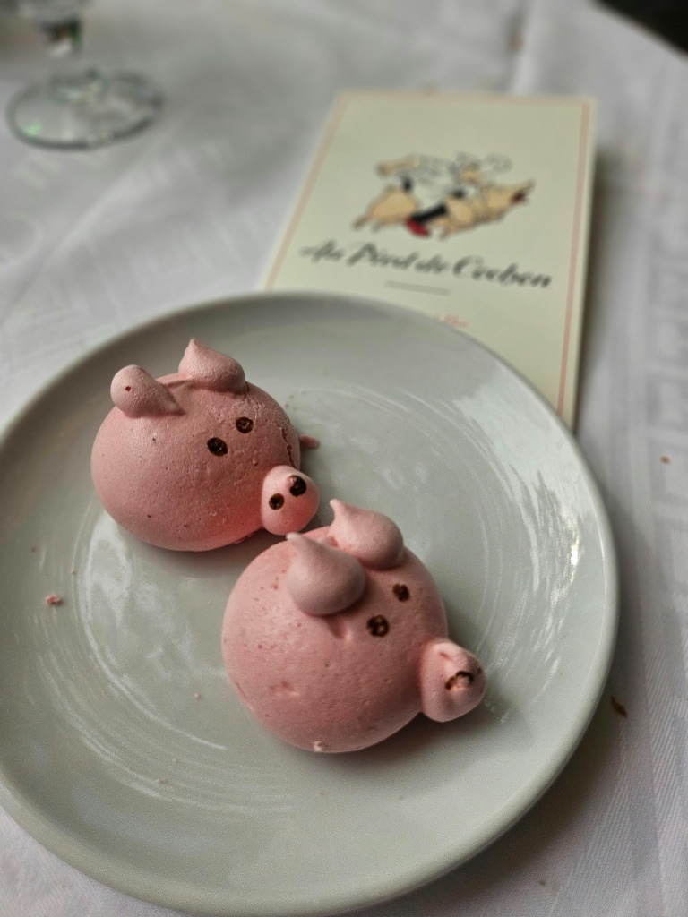 Pink pig meringues on a saucer with Au Pied de Cochon menu card